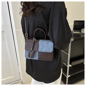 Bruin lederen en blauwe denim patchwork handtas gedragen als crossbody door een model