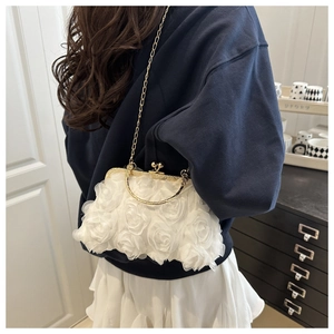 Close-up of white chiffon rose petal handbag with gold chain strap worn by a model