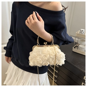 Detail of elegant white evening clutch with 3D floral textures and gold metal handle