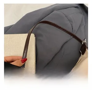 Close-up of high-quality dark brown leather strap with silver metal buckle on tote bag