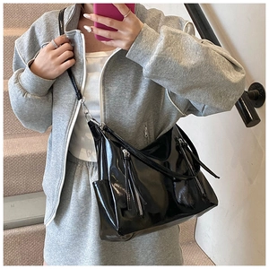 Glossy black patent leather tote bag with metallic zippers shown in a style selfie