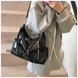 Detail of black patent leather handbag with vertical metal zipper and strap accents