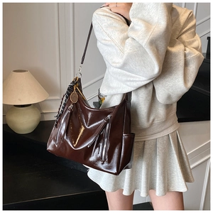 Detail of dark brown glossy patent leather tote with decorative tennis racquet charm