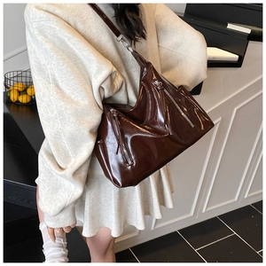 Detailed view of dark brown high-gloss leather shoulder bag with silver zippers