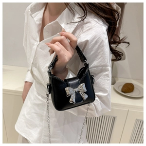 Nahaufnahme einer schwarzen Mini-Handtasche mit silberner Schleifenschnalle und Kette