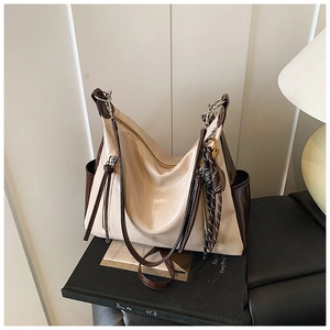 Macro detail of glossy cream leather hobo bag with vintage coffee brown trim and striped charm