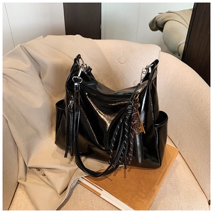 Detail of a large black glossy tote bag with stylish tassels and multi-pocket design