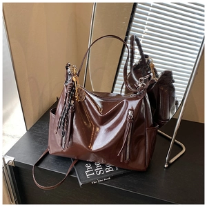 Detail of dark brown glossy tote bag with dual zippers and decorative tennis racket pendant