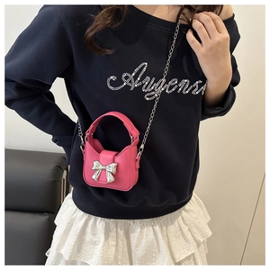 Detail einer pinkfarbenen Mini-Umhängetasche mit silberner Metallschleife und Kette