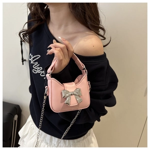 Detailansicht der rosa Mini-Handtasche mit silberner Schleife und feiner Kette