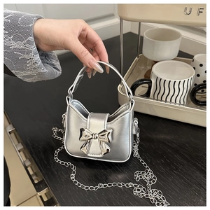 Nahaufnahme der metallisch silbernen Mini-Handtasche mit Schleife und Kettenriemen