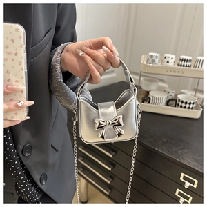 Detailaufnahme einer Mini-Handtasche in Silber mit Metallschleife und feiner Kette