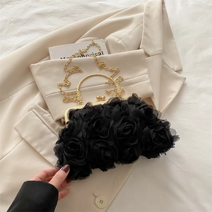 Detail of elegant black chiffon 3D rose evening bag with a gold round handle and chain