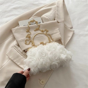 Detail of white 3D rose petal handbag featuring a gold ring handle and metal chain strap