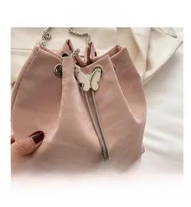 Close-up of pink bucket bag with pleated texture and silver butterfly charm
