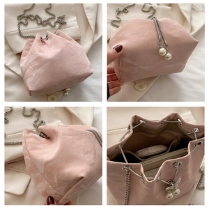 Detail view of pink drawstring bucket bag featuring pleated texture and pearl chain strap