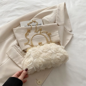 Close-up of cream floral evening clutch bag with 3D mesh roses and golden handle