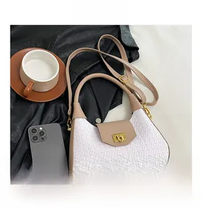 Macro shot of white woven texture and leather crescent bag with golden twist lock detail