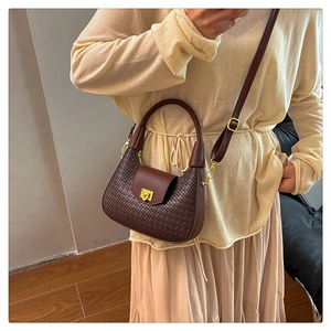 Detail of brown woven crescent bag with golden buckle and adjustable strap
