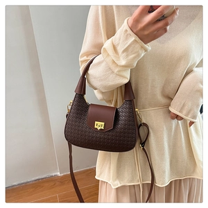 Detail of dark brown woven texture handbag with golden metal lock and shoulder strap