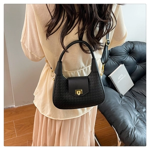 Detail of a black woven crescent bag with gold buckle and adjustable shoulder strap