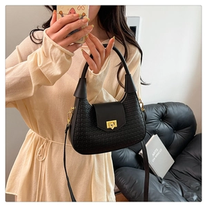 Detail of black woven texture handbag with golden twist lock and slim shoulder strap