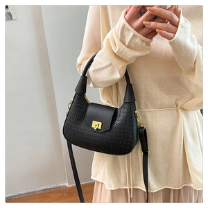Close-up of woven texture on black crescent bag with golden twist lock and smooth flap