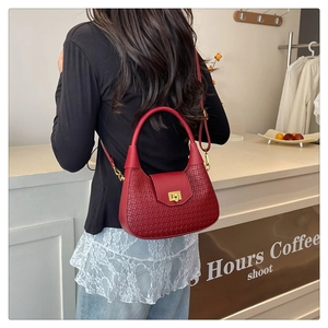 Detail of red woven crescent bag featuring a gold metal twist lock and shoulder strap