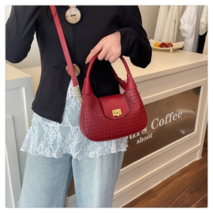 Detail of red crescent bag showing woven texture, smooth leather, and gold twist lock