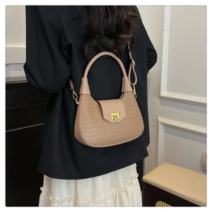 Detail of beige woven texture crossbody bag with gold buckle on elegant model