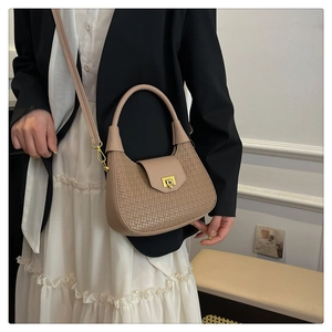 Detail of taupe woven leather shoulder bag with gold twist lock on black blazer outfit