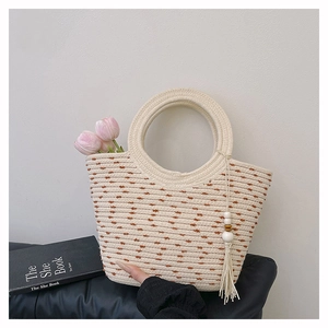 Dettaglio della borsa tote intrecciata a pois marroni con manico tondo e nappa di legno