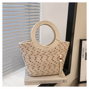 Détail du sac à main en paille tressée avec pois marrons et pompon en perles