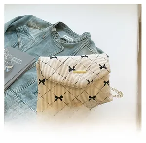 Close-up of corduroy crossbody bag featuring black bow embroidery and gold chain strap