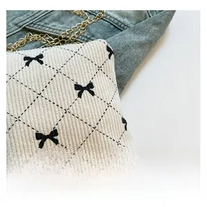 Detail of cream corduroy crossbody bag with diamond quilting and black bow embroidery