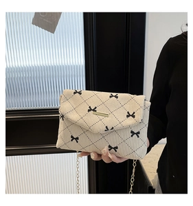 Dettaglio borsa a tracolla in velluto beige con fiocchi neri e catena dorata