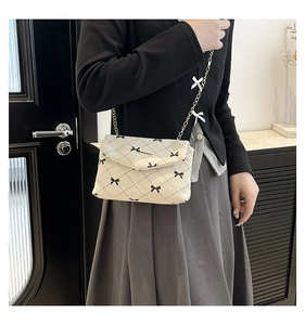 Detail of beige corduroy crossbody bag with black argyle pattern and gold chain strap