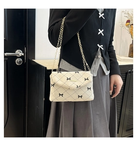 Detailed close-up of cream corduroy crossbody bag featuring black plaid and bow embroidery