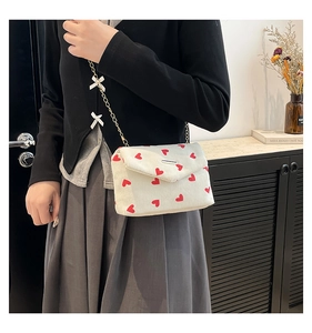 Close-up of white corduroy heart print handbag with bow-decorated gold chain strap