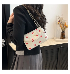 Detail of corduroy envelope bag with red heart pattern and golden chain strap