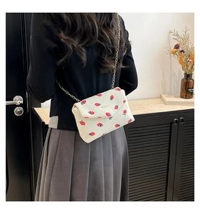Detail of corduroy shoulder bag with strawberry print and gold metal chain strap