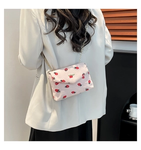 Pink corduroy crossbody bag with strawberry print and gold chain strap on model