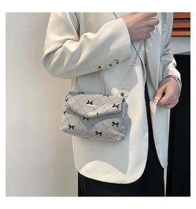 Detail of light grey corduroy crossbody bag with black bows and gold chain strap