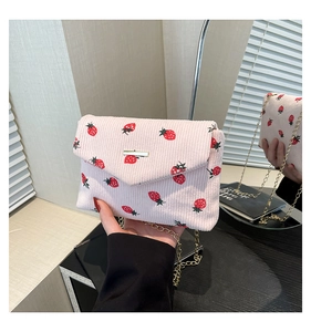 Close-up of pink corduroy small square bag with strawberry print and gold chain strap