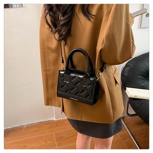 Detail of black quilted PU leather crossbody bag with elegant gold branding and shoulder strap