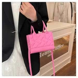 Detail of rose pink quilted crossbody bag with cross-stitch texture and elegant top handles