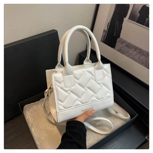 Detail of white quilted PU leather handbag with FASHION & BAGS logo and strap