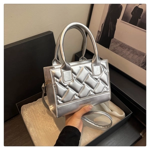Detail of silver quilted PU handbag with metal finish and round top handles