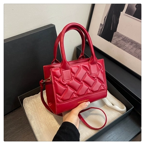 Detail of red quilted PU leather handbag with dual handles in a premium gift box setup