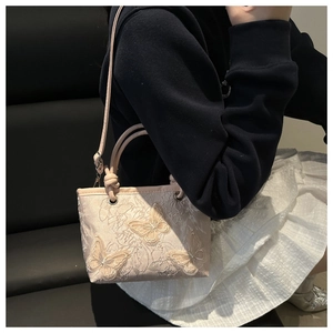 Detail of floral lace texture and 3D butterfly embroidery on mini bucket bag